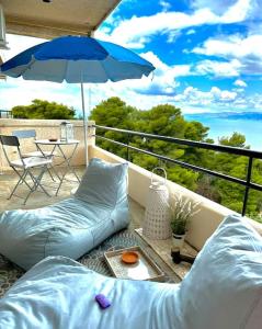 a balcony with a couch and an umbrella and a table at SeaTerra Boutique suite in Kalamos