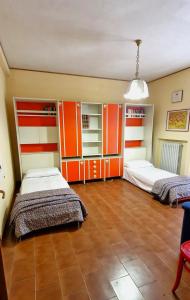 2 Betten in einem Zimmer mit orangefarbenen und weißen Schränken in der Unterkunft La Corte sul Conero Casa Vacanze in Camerano
