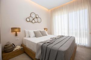 a white bedroom with a large bed and a window at Muses of art Villas in Afantou