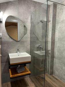 uma casa de banho com um lavatório e uma cabina de duche em vidro. em The Stone Sky Hotel em Gjirokastër