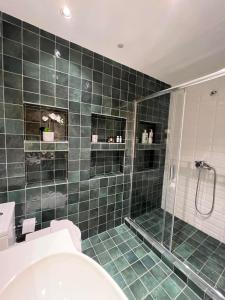 a bathroom with a green tiled shower and a toilet at Crown Syntagma Apartment in Athens
