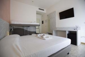 a bedroom with a white bed with a tv on the wall at Hotel Confort in Rimini