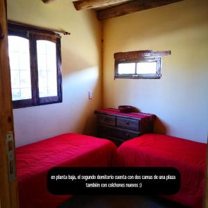 a bedroom with two red beds and a window at Reposo del Huasamayo in Tilcara