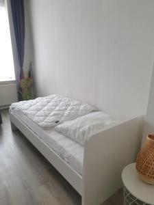 een wit bed in een kamer met een witte muur bij FeWo Nina in Weißenfels