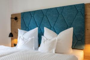 a bed with white pillows and a large headboard at Ferienwohnungen Assenmacher mit Sauna in Altenahr