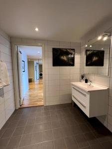Baño blanco con lavabo y espejo en Seaside Central Apartment, en Osøyro