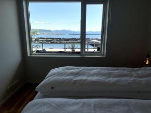 1 dormitorio con cama y ventana grande en Seaside Central Apartment, en Osøyro