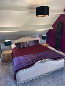 a bedroom with a bed with purple sheets and two lamps at The Coach House 1861 in Penrith