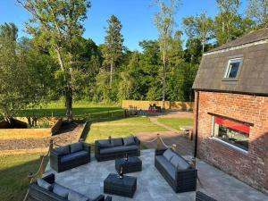 a patio with black couches and a brick building at The Coach House 1861 in Penrith