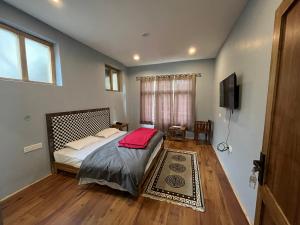 1 dormitorio con 1 cama y TV de pantalla plana en Honey Bee en Leh