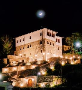 un grande edificio con luci di notte davanti di The Stone Sky Hotel a Gjirokastër