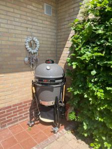 a grill sitting on a brick patio next to a bush at Holiday Home Beo in Oostkapelle