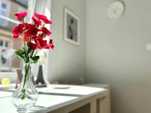 um vaso cheio de flores vermelhas sentado num balcão em MMRent Shadow Room em Gdansk