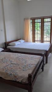 two beds sitting in a room with windows at The Village Courtyard- Organic farm & homestay in Pīrmed