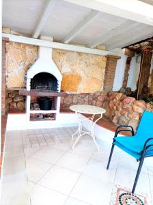 a patio with a table and a stone fireplace at Sardinia Yellow House in Solanas