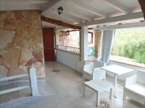 a room with a table and chairs and a stone wall at Sardinia Yellow House in Solanas