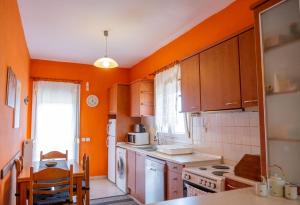 a kitchen with orange walls and a table and a kitchen with a stove at Natural Oasis Villa in Nea Fokea +12 photos
