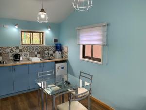 a blue kitchen with a glass table and chairs at Cabañas Raupa in Hanga Roa