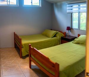 2 Betten in einem Zimmer mit grüner Bettwäsche in der Unterkunft Cabañas Raupa in Hanga Roa