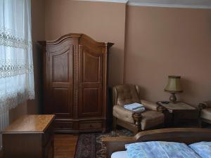 a bedroom with a large wooden cabinet and a chair at Вілла де Кампо in Chynadiyovo