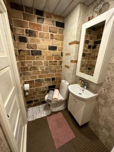 a bathroom with a brick wall and a toilet and sink at Sadama Apartement Haapsalu in Haapsalu