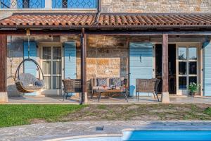 een huis met een patio met stoelen en een schommel bij Villa Paolina in Višnjan