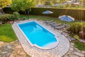 a swimming pool with two umbrellas and two chairs and a swimming pool at Villa Paolina in Višnjan