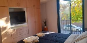 sypialnia z łóżkiem, telewizorem i oknem w obiekcie Moderno departamento w mieście Godoy Cruz