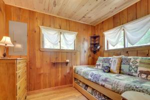 1 dormitorio con paredes de madera y 1 cama con ventana en Charlevoix Cabin with Patio and Grill - Steps to Lake! en Charlevoix