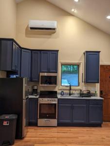 una cocina con armarios azules y fregadero en Oak Treehouse Cabin Rustic Luxury Near Asheville, en Marshall