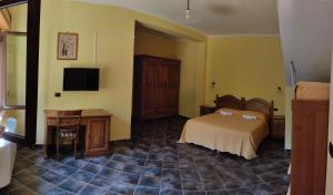 - une chambre avec un lit, un bureau et une télévision dans l'établissement Agriturismo Roseto, à Serra San Bruno