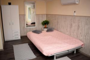 1 dormitorio con 1 cama grande con sábanas rosas y espejo en Liliom Apartman, en Balatonvilágos
