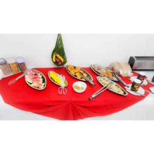 einen Tisch mit Teller mit Lebensmitteln auf einem roten Tischtuch in der Unterkunft OEManagement Hotel Rooms in Roseau