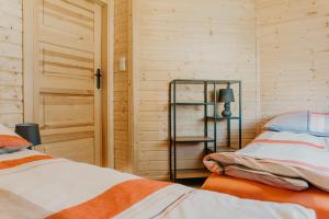 a bedroom with two beds and a lamp and a door at Domki Sunset Lubiatowo in Lubiatowo