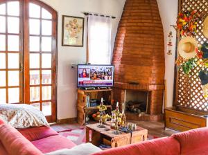 a living room with a tv and a fireplace at Chalé com Piscina em Piranguçu - Serra Mantiqueira in Piranguçu