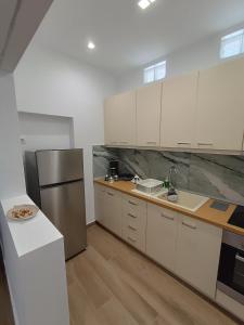 eine Küche mit weißen Schränken und einem Kühlschrank aus Edelstahl in der Unterkunft Selinia Residence in Selínia