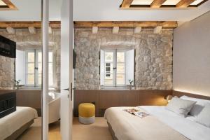 a bedroom with two beds and a stone wall at Villa Lapisa in Dubrovnik