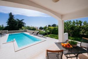 - une piscine sur une terrasse avec une table et des chaises dans l'établissement Villa Kata, à Zadar