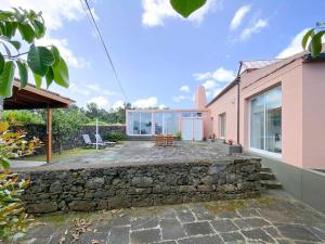 a home with a stone retaining wall and a patio at Capelas House Family in Capelas