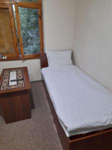 a small bedroom with a bed and a table at Shahina tur service in Samarkand