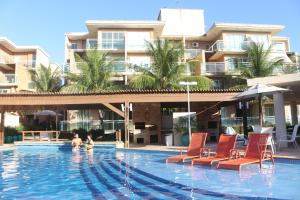 a swimming pool with chairs and a building at PALM BEACH Porto das Dunas, apartamento todo climatizado TÉRREO a 350 metros Beach Park in Aquiraz