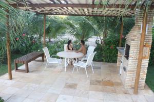 dos personas sentadas en una mesa en un patio en PALM BEACH Porto das Dunas, apartamento todo climatizado TÉRREO a 350 metros Beach Park, en Aquiraz