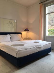 a large bed in a bedroom with a window at Ville Lago Lugano in Porto Ceresio