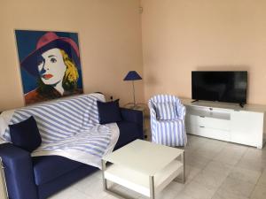 a living room with a blue couch and a tv at Ville Lago Lugano in Porto Ceresio