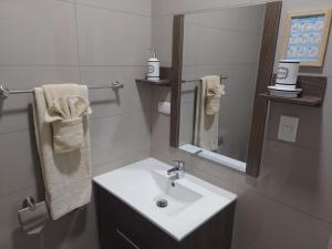 y baño con lavabo, espejo y toallas. en Apart Hotel Campos Rancagua, en Rancagua