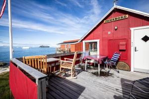 a red building with a table and chairs on a deck at Ilulissat Stay - Jomsborg Ilulissat in Ilulissat