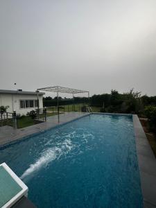 uma piscina com água azul num quintal em Luxury Farmhouse Stay, Pure Vegetarian- Santushti Farm, NCR em Tibri