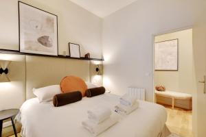 - une chambre avec un lit blanc et des serviettes dans l'établissement Charming 1-BEDR Parisian Apartment in Vibrant Rue d'Hauteville, à Paris