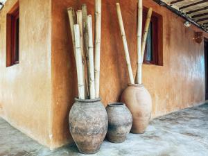 three vases sitting next to a wall with bamboo poles at El Sitio de Playa Venao in Playa Venao