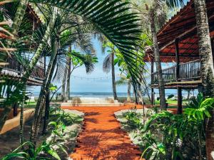 a pathway through a resort with palm trees and the ocean at El Sitio de Playa Venao in Playa Venao